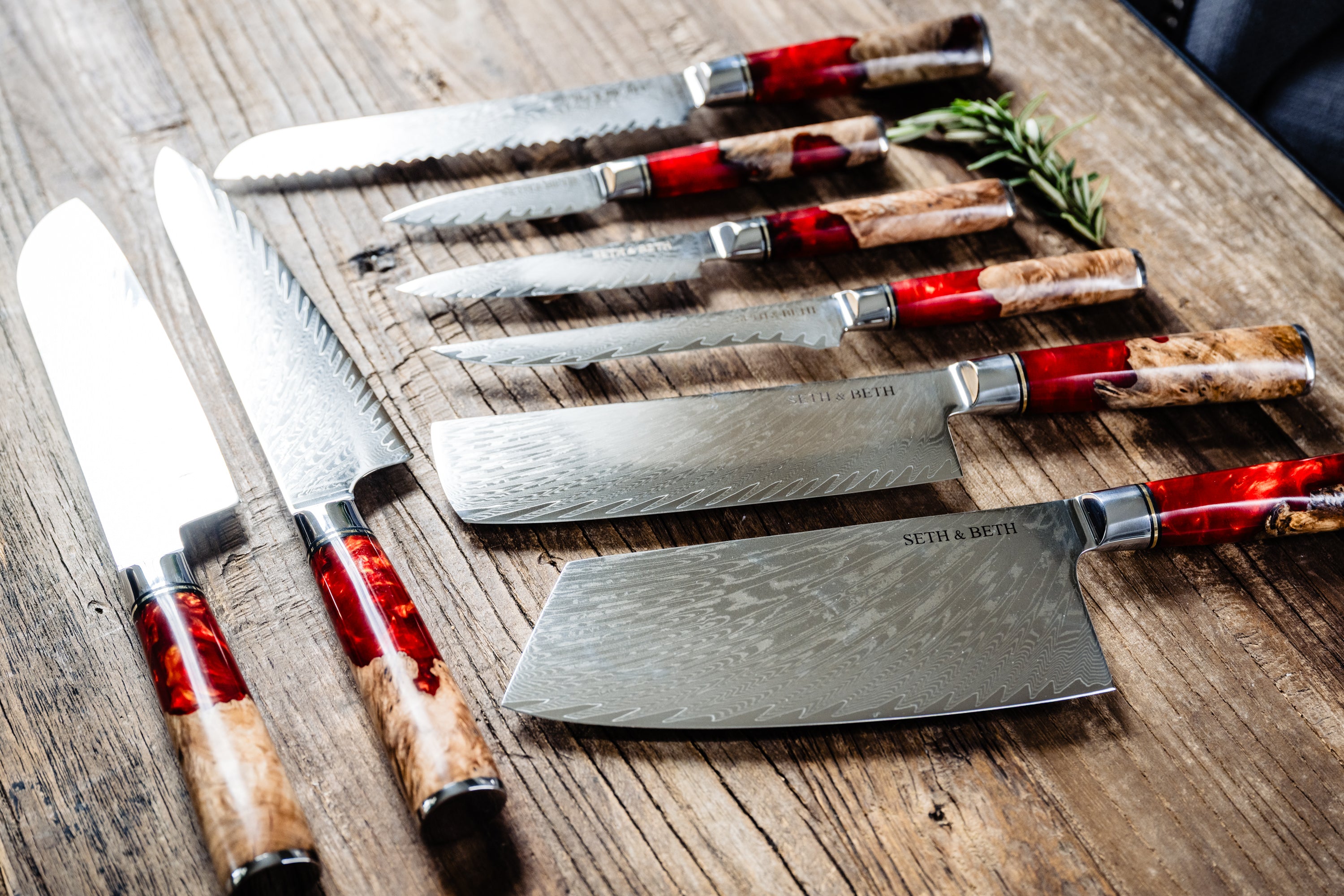 Red burl handle engraved Damascus knife set displayed on wooden surface — Tidal Collection