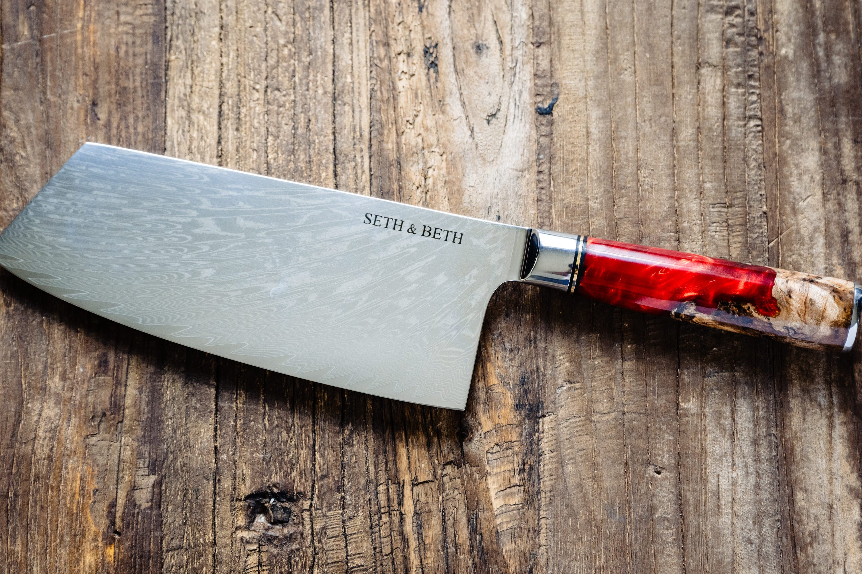 Red burl handle engraved Damascus knife set displayed on wooden surface — Tidal Collection